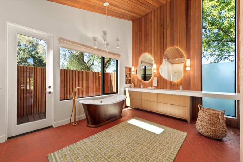 Custom bathroom with wood-paneled ceiling and freestanding copper tub